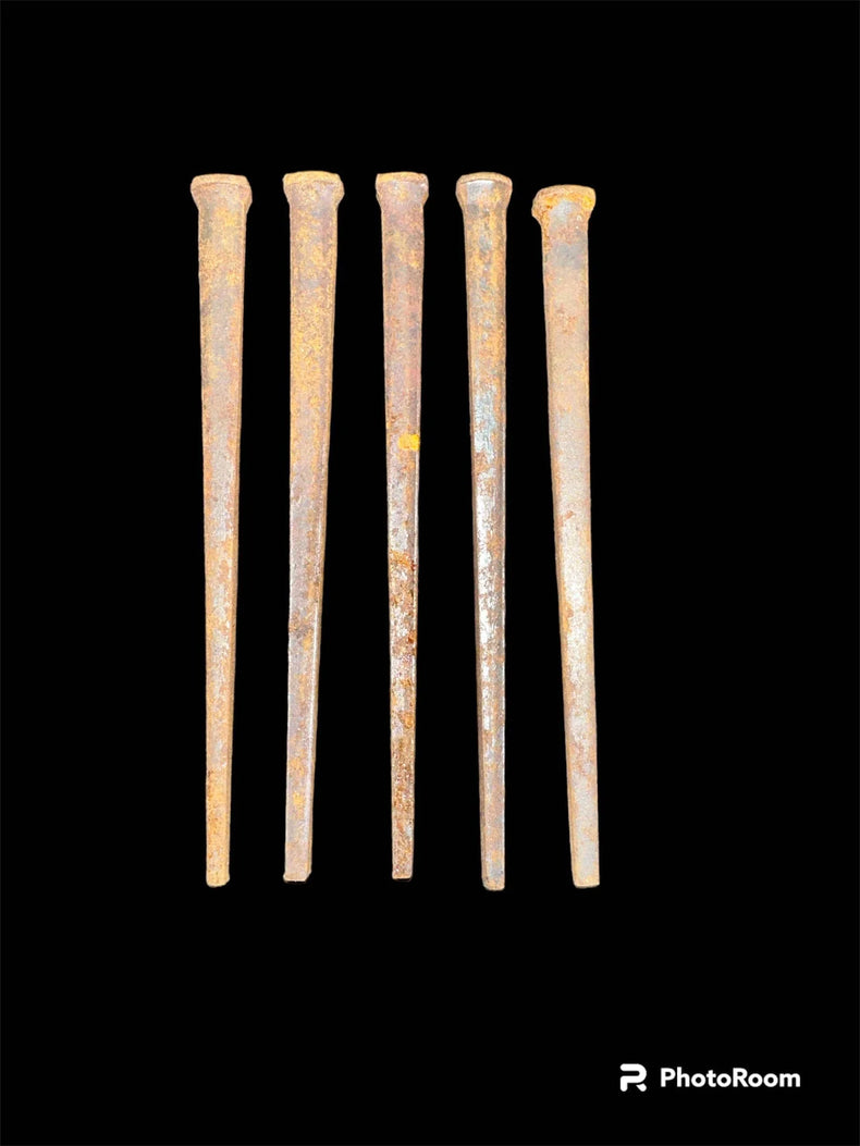 Five rusty iron nails aligned vertically on a black background, vintage metaphysical decor.