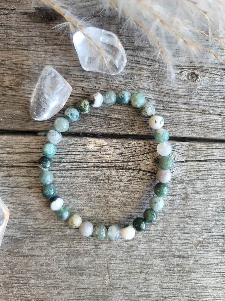 Moss agate crystal bead bracelet with clear quartz stones on rustic wood background
