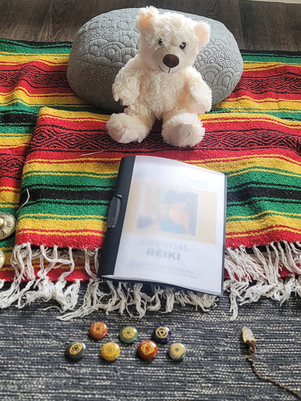 Colorful striped blanket with a teddy bear, electronic device, and buttons on a textured surface.