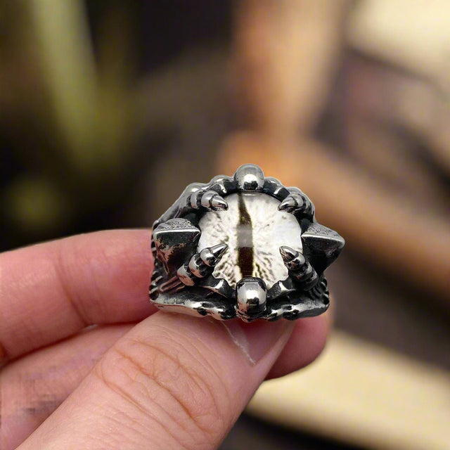 Silver ring with unique design held in a hand against a neutral background