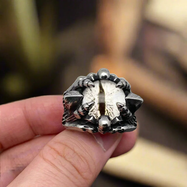 Silver ring with unique design held in a hand against a neutral background