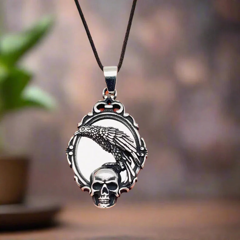 Silver skull pendant held in a hand against a white background