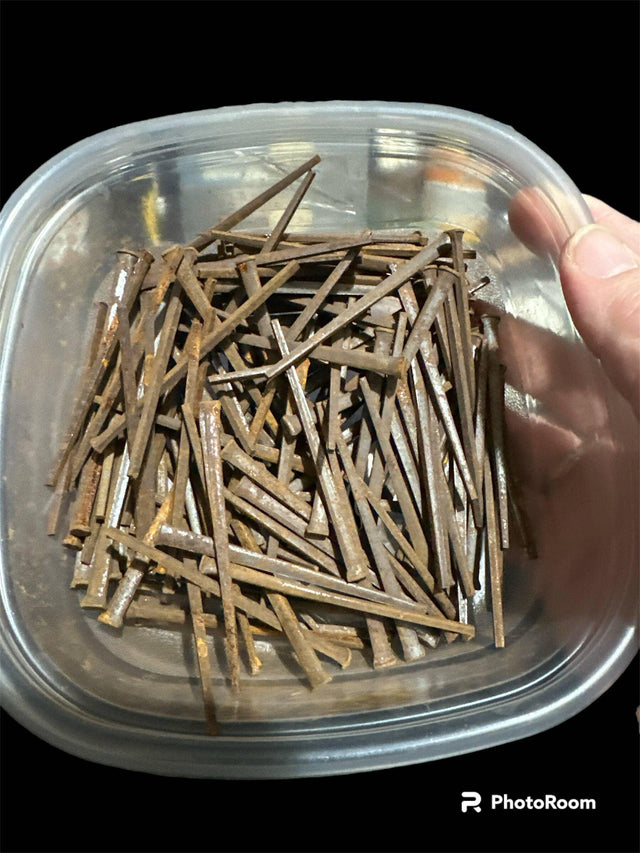 Hand holding container filled with rusty iron nails, metaphysical supplies background