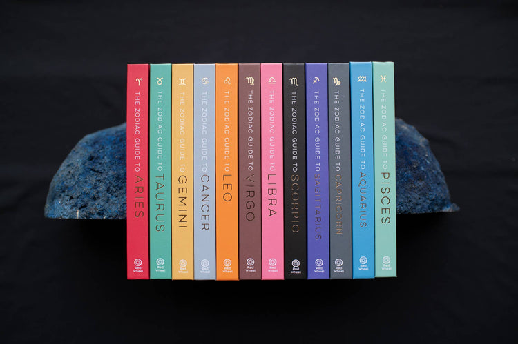Colorful set of zodiac guide books for each astrological sign on a dark background