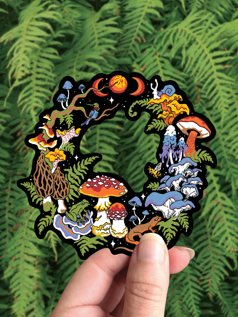 Mushroom Fairy Ring vinyl sticker, a cut through circle of mushrooms, snails and moon phases, held against ferns