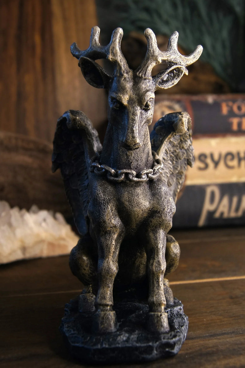 Winged stag statue with antlers and chain, mystical decor on wooden table