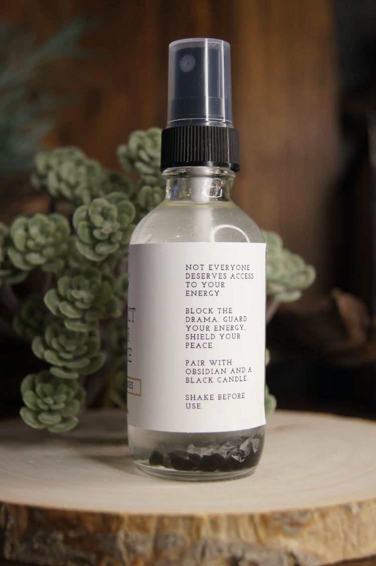 Crystal-infused energy clearing spray bottle with text, displayed on wood with succulents.