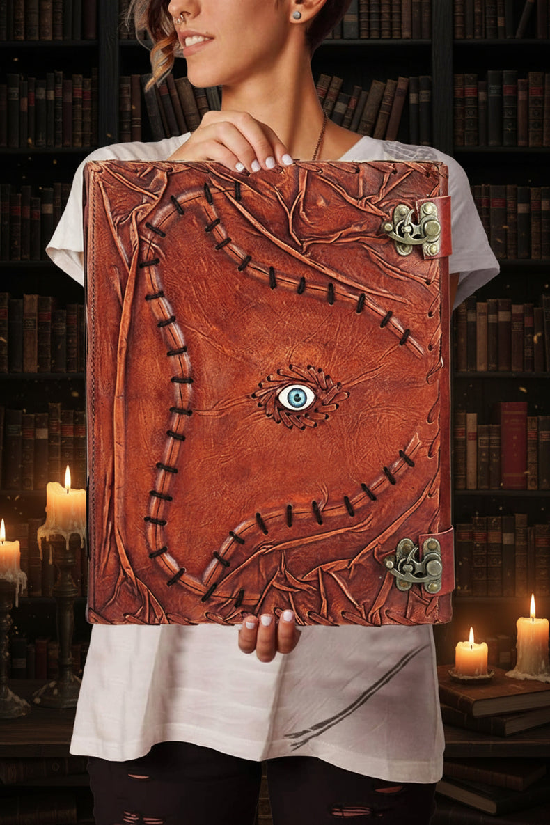 Handmade leather grimoire with embossed vines, blue eye charm, and metal clasps for witchcraft or tarot journaling