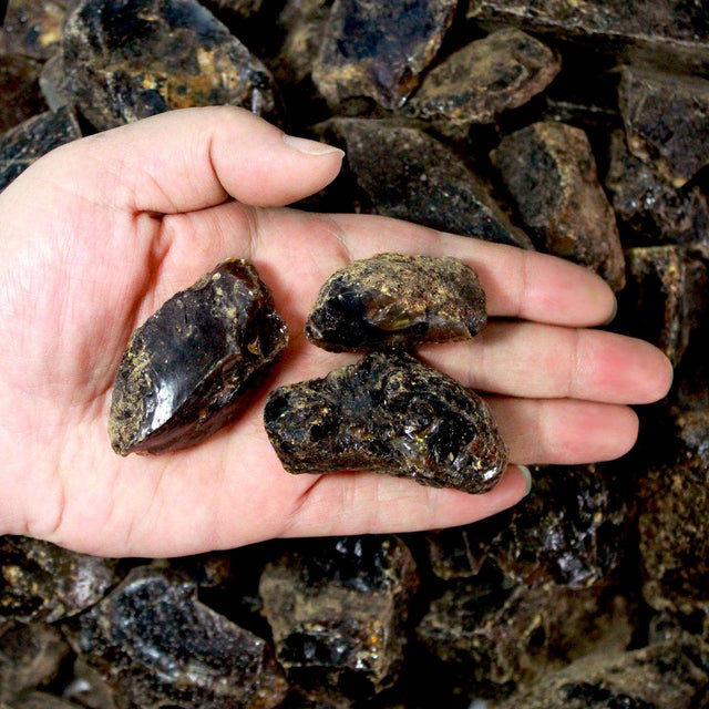 Hand holding raw brown-black smoky quartz healing crystals