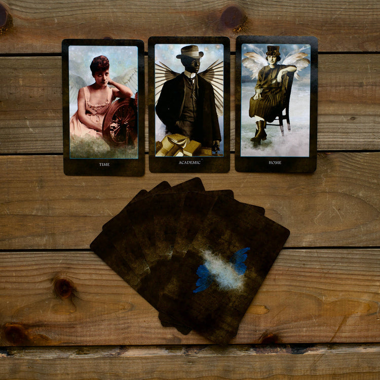 Three tarot cards with vintage angel figures and keyword labels on wooden table