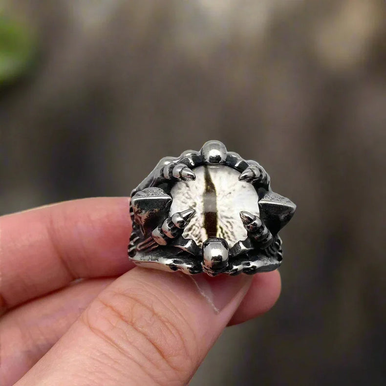 Silver ring with unique design held in a hand against a neutral background