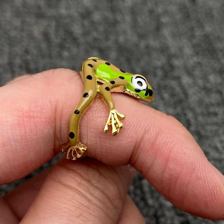 Gold and green enamel frog ring with black spots wrapped around a finger