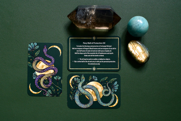 Tarot cards with mystical snake designs, healing crystals, and a protection oil recipe on green background.