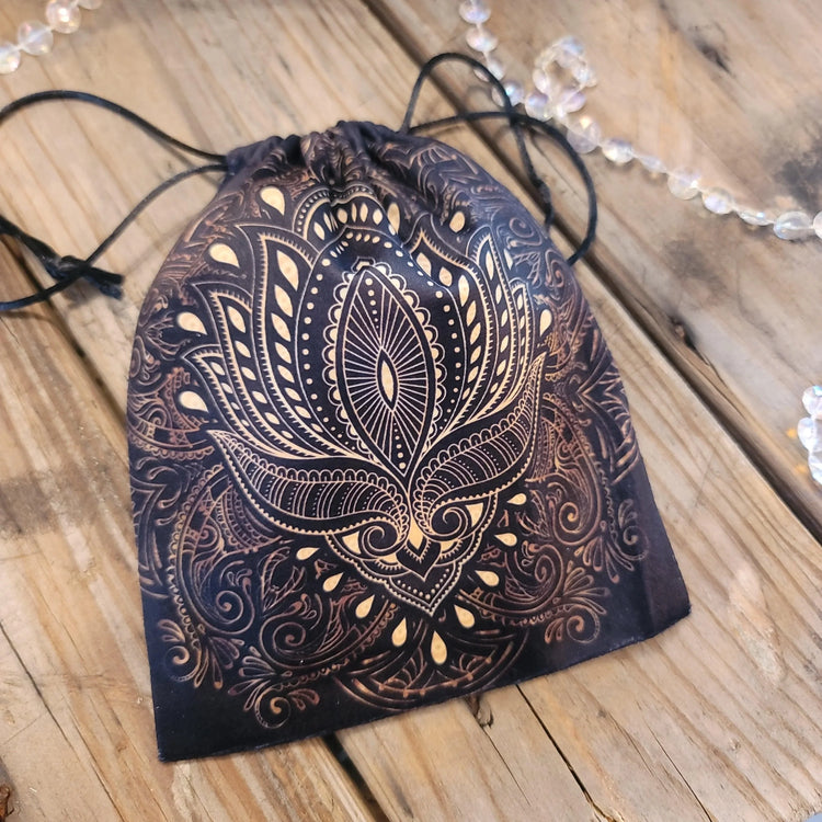 Black tarot card pouch with intricate gold mandala design on rustic wood background
