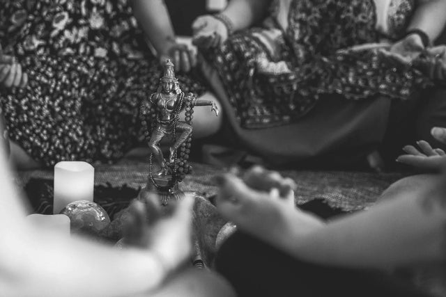 Meditation circle with candles, crystal ball, goddess statue, and people seated cross-legged