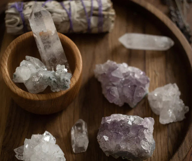 Assorted healing crystals, amethyst, and sage bundle on wooden tray for metaphysical use