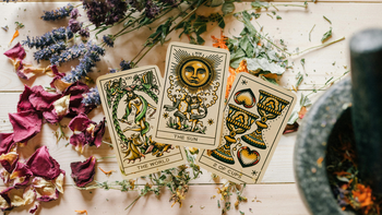 Tarot cards with dried flowers and herbs on a wooden table, metaphysical decor