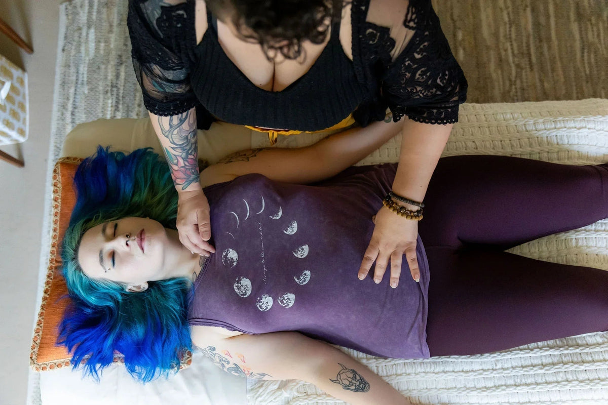 Woman with blue hair receiving Reiki energy healing therapy on a massage table