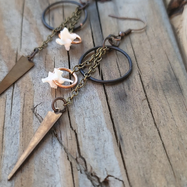 Boho bronze dangle earrings with white star charm, chains, and rings on rustic wood