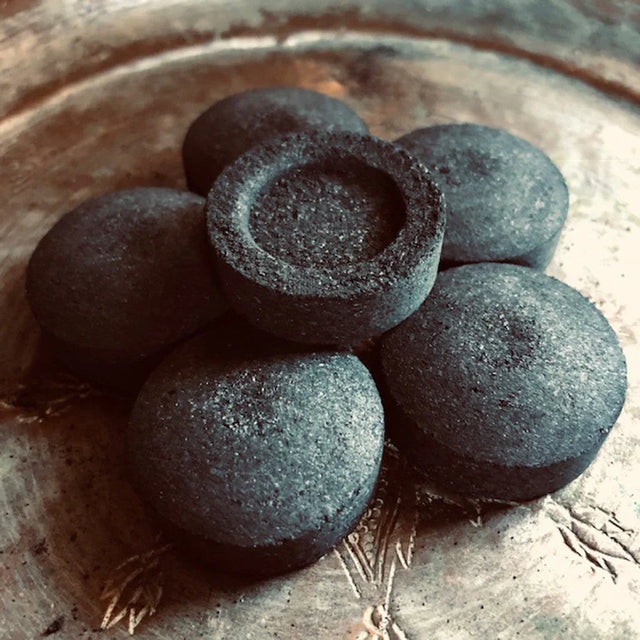 Charcoal disks for incense burning arranged on a decorative metal tray.