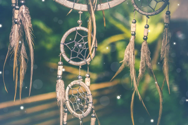 Close-up of dreamcatcher with feathers and beads, hanging outdoors in soft sunlight