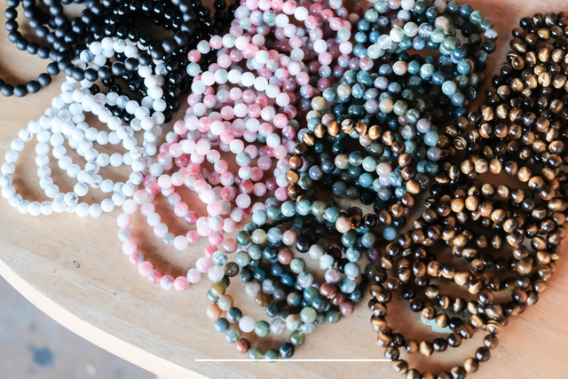 Assorted gemstone bead bracelets in various colors on a wooden surface
