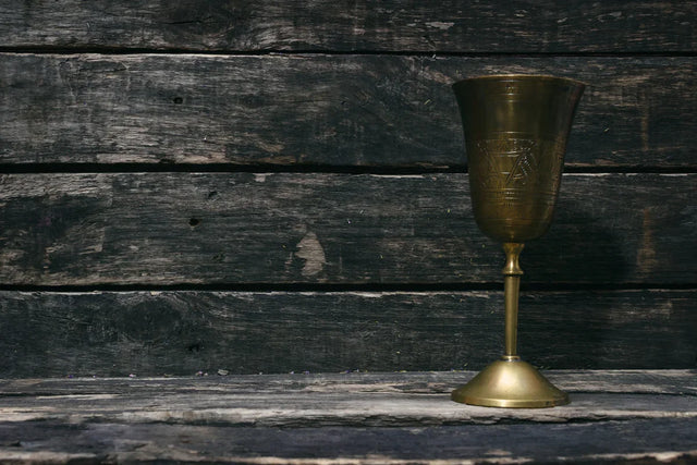 Antique ceremonial brass chalice on rustic wooden table for spiritual rituals or altar use