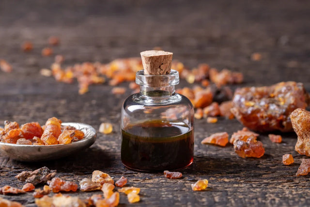 Glass bottle of essential oil with myrrh resin chunks on rustic wooden table, aromatherapy