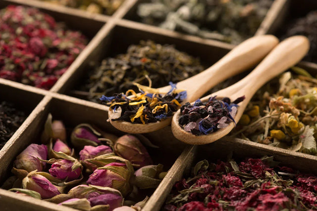 Assorted dried herbs and flowers in wooden box with wooden spoons, herbal apothecary supplies