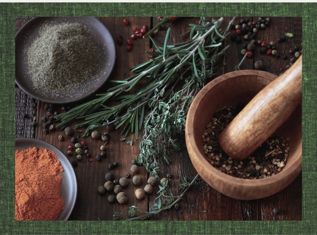 Assorted herbs, spices, peppercorns, and a mortar and pestle on a rustic wooden table