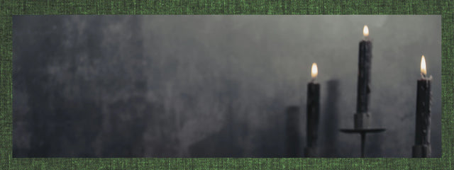Three black ritual candles burning with flames against a dark textured background