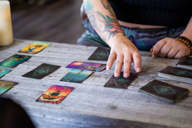 Person doing tarot card reading on rustic wooden table with colorful deck