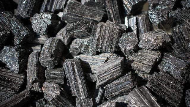 Raw black tourmaline crystals with natural striations and shiny texture.