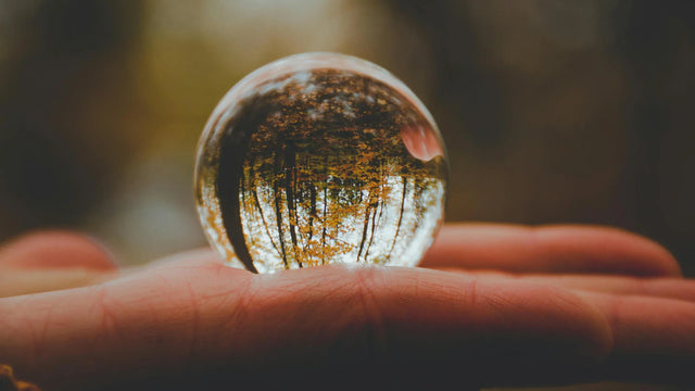 Crystal sphere reflecting autumn forest held in a hand, metaphysical crystal imagery