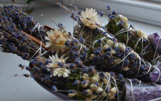 Herbal incense bundles with dried lavender, flowers, and crystals in natural light