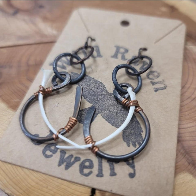 Handmade wire-wrapped dangle earrings with black, copper, and white metal rings.