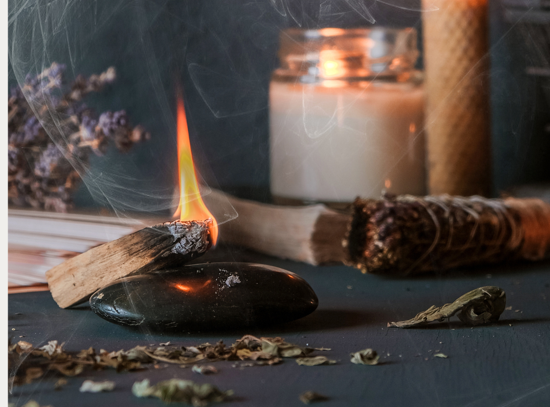 Burning palo santo stick, crystals, sage bundle, and candles for meditation or healing