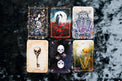 Six tarot cards with skeleton and skull illustrations on a dark velvet background