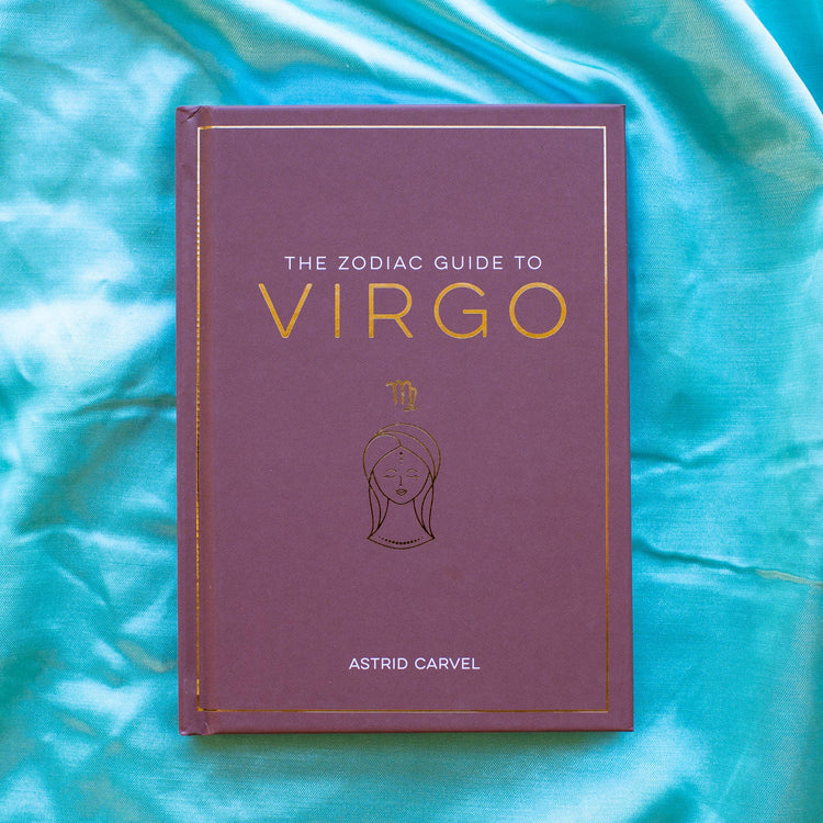 Purple Zodiac Guide to Virgo astrology book by Astrid Carvel on blue silk fabric