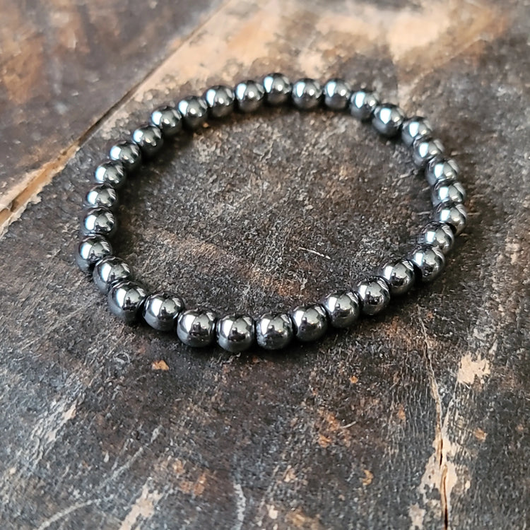 Hematite beaded stretch bracelet on rustic wooden surface, crystal healing jewelry