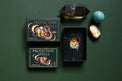 Protection Spells card deck with illustrated snake design, crystal points, and polished stones on green background