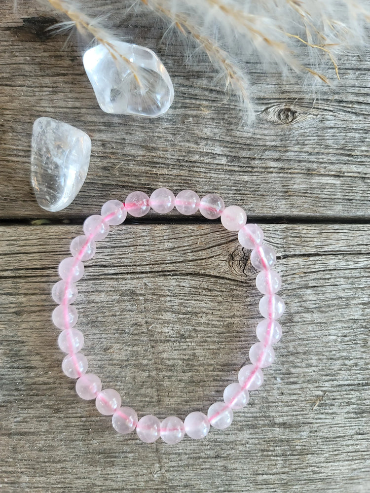Rose quartz beaded bracelet with clear tumbled crystals on rustic wood background