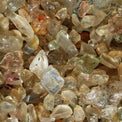 Close-up of raw quartz crystals with clear, earthy, and amber hues.