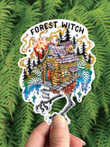 Baba Yaga Forest Witch vinyl sticker, the hut on chicken legs in a pine forest, held against ferns