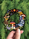 Mushroom Fairy Ring vinyl sticker, a cut through circle of mushrooms, snails and moon phases, held against ferns