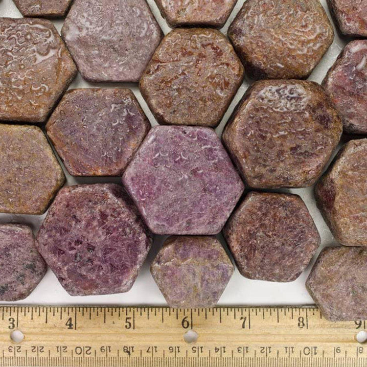 Hexagonal raw ruby crystals arranged with a wooden ruler for scale