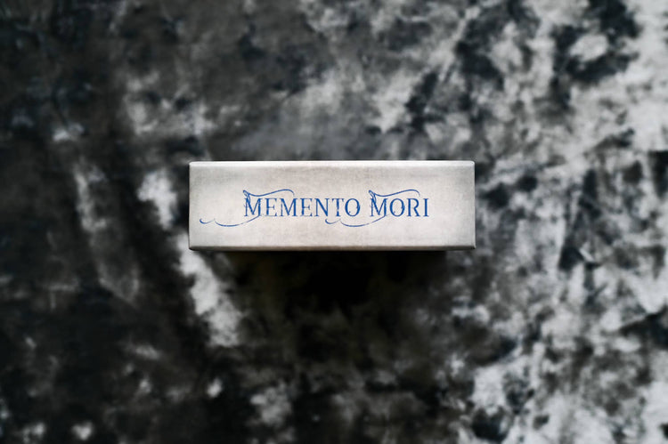 Memento Mori tarot deck box on a dark textured background