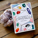The Little Book of Crystals with an amethyst cluster on a wooden surface