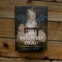 The Beloved Dead oracle deck box with ethereal chair and mystical design on wood background.
