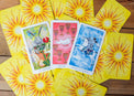 Colorful tarot cards including Empress, Nine of Cups, and Knight of Swords on wooden table